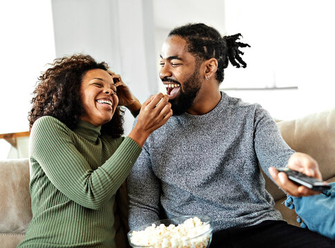 Portrait of a happy young couple watching tv together at home. Shot of a couple resting on the couch watching television