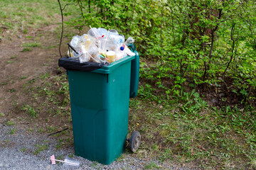 The garbage container on wheels is completely filled with garbage.