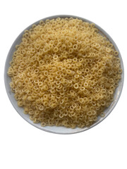 Top view of dry ring-shaped pasta in white plate isolated on white background — raw anellini pasta for soup or traditional recipes

