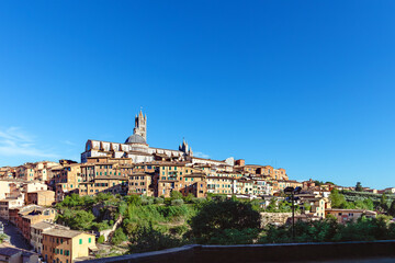 Vibrant medieval architecture and hills surround the stunning Cathedral of Siena in Italy under a clear blue sky. Siena, Toscana, Italy