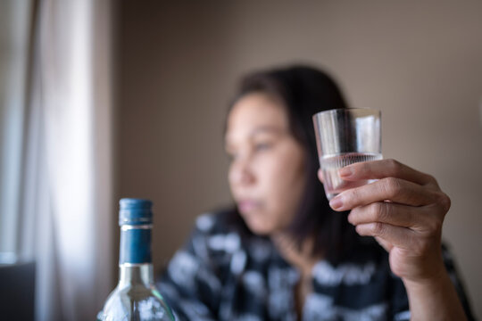 Hand of woman holding shot glass of gin