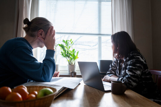 Stressed mature couple sitting at table in home