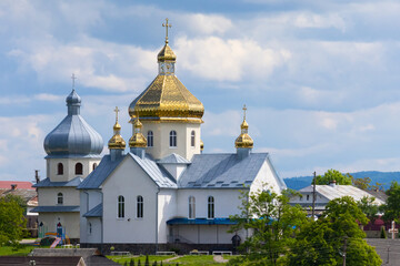 Fototapeta na wymiar Stunning view of a traditional Eastern Orthodox church with golden and silver domes under a cloudy blue sky