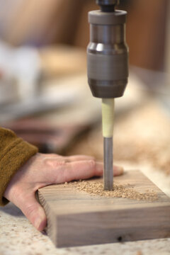 Close-up of carpenter drilling wood block in woodshop