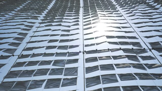 Dynamic kinetic facade moving in sunlight for modern sustainable building design.