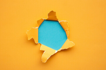 Torn ripped yellow paper hole on blue background