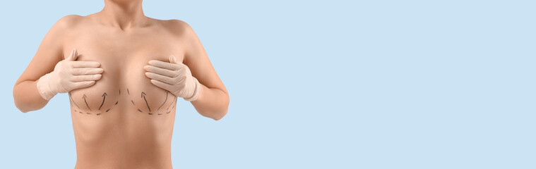 Naked young woman in medical gloves with marks on her breasts against blue background, closeup....