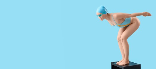 Female swimmer in start position on light blue background with space for text