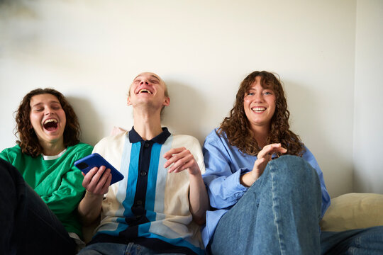 Portrait of young woman enjoying leisure time with carefree friends in bedroom at home