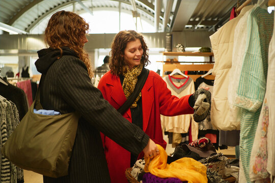 Young female friends shopping for clothes in clothing store