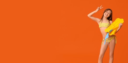 Happy little girl in swimsuit and with flippers showing victory gesture on orange background with space for text © Pixel-Shot