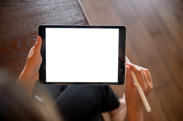 Top view close up of hand holding white screen tablet with a stylus on table in cafe or coffee shop.