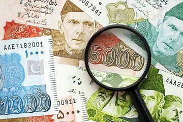 Pakistan rupees banknotes and magnifying glass. The current Pakistan money bills with loupe