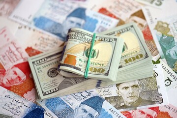 Bunch of US dollar bills lies on big amount of Pakistan rupees banknotes close up