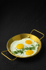 Fried eggs with herbs in pan.
