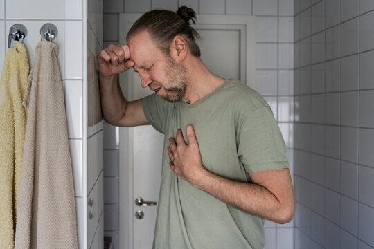 Painful man having chest problems while standing in bathroom