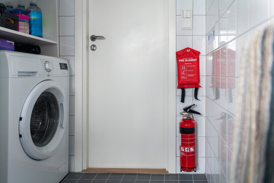 Fire extinguisher and fire blanket hanged on tile in bathroom