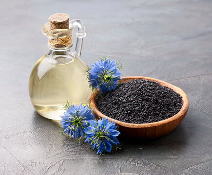 Black cumin oil in a bottle and nigella flower