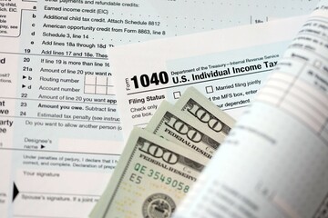Hundred dollar bills and 1040 individual income tax return form blank close up