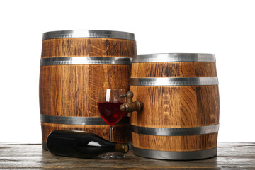 Wooden barrels with bottle and glass of wine on table against white background