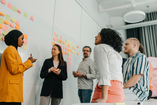 Low angle view of curly haired businesswoman sitting in meeting with colleagues at office
