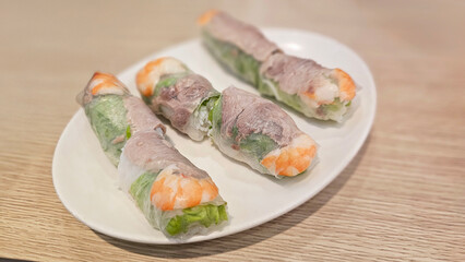 Eating delicious traditional food — Vietnamese fresh spring rolls: rice paper and vermicelli, vegetables, pork, seafood, lettuce, cucumber, herbs, shrimp, tangy fish sauce with lemon