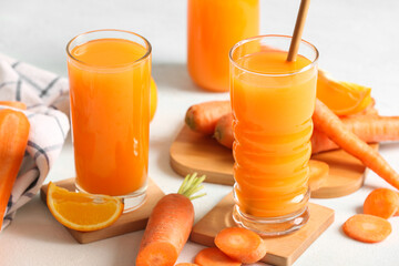 Glasses of fresh carrot juice on light blue table