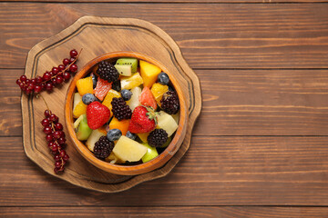 Bowl of fresh fruit salad on wooden background