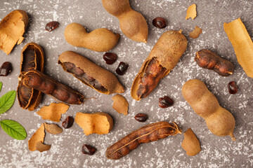 Tasty tamarinds and seeds on grey background