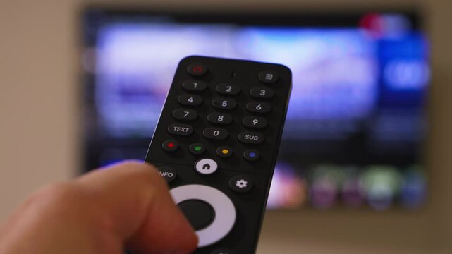 Male hand holding the TV remote control and turn on smart tv. Switching channels. High quality 4k footage