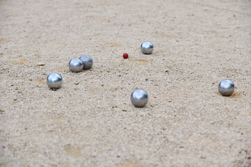 Petanque balls scattered on a gravel court around a small target ball cochonnet during a game. Outdoor sports scene, focused on strategy and precision