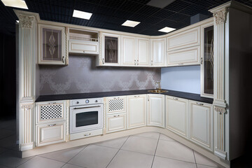 Interior of modern classic style kitchen in beige colors with golden sink basin. Drawers cabinets with lattice and golden decoration. Dark stoneware empty countertop. Built-in appliances electric oven