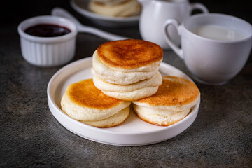 Delicious breakfast: fluffy pancakes on a white plate on a gray background. Japanese pancakes for dessert. Close-up