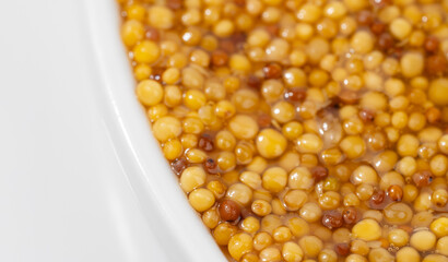 French Dijon mustard in a metal spoon, top view on mustard grains background. Gastronomy concept,...