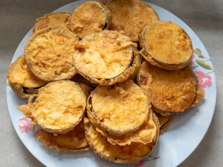 Home made deep fried sliced aubergine in batter served on a plate.