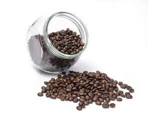 Roasted coffee beans in glass jar on white background