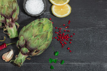 Fresh green artichokes cooking on wooden background. Traditional seasonal ingredients