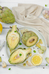 Fresh green artichokes cooking on wooden background. Traditional seasonal ingredients