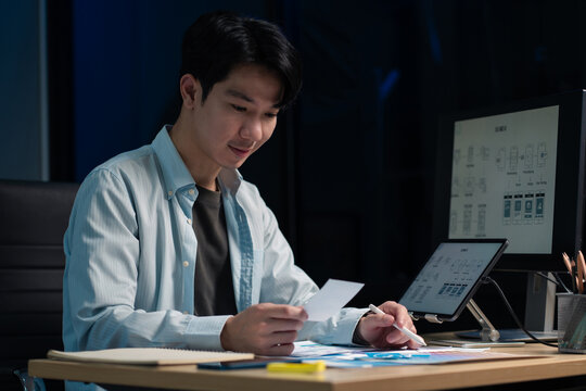 Male coder or developer working overtime using a computer display in problem solving at workplace.