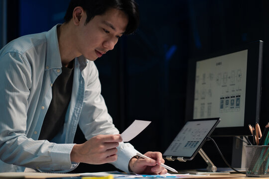 Male coder or developer working overtime using a computer display in problem solving at workplace.