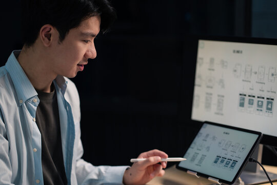 Male coder or developer working overtime using a computer display in problem solving at workplace.