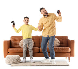 Happy father and his son playing video games near brown leather sofa against white background