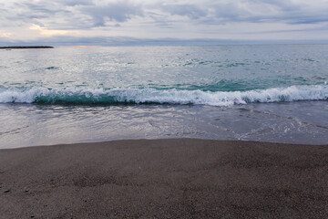 Sea surf waves on a sandy shore in overcast morning