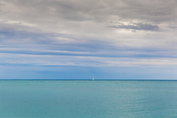 Sea water surface with distant sailing yacht on a horizon