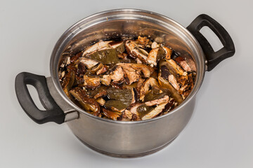 Dried boletus soaked in stainless steel saucepot on gray background