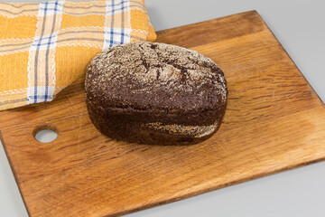 Whole brown bread on wooden cutting board on gray surface