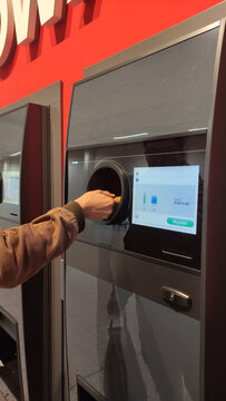 Warsaw, Poland - May 31, 2025: Hand inserting bottle into recycling machine with digital interface display