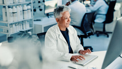 Computer, medical and science with woman in laboratory for online development or research. Innovation, smile and typing with mature scientist at desk for breakthrough, clinical trial or experiment