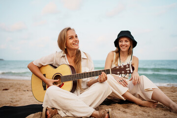 Two Friends Happily Enjoying Music Together on the Beach During a Beautiful Sunset