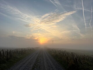sunrise over the road with wind turbine in the morning fog